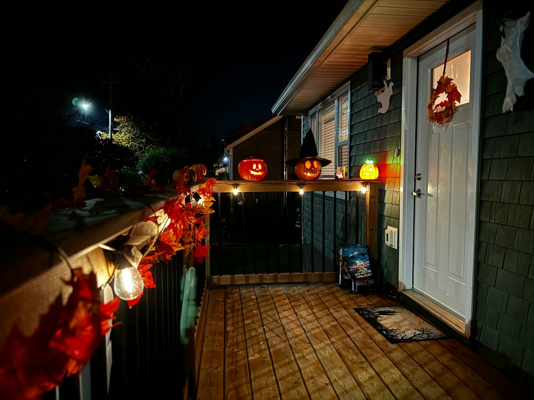 Halloween porch with warmly lit jack-o-lanterns and autumn decorations